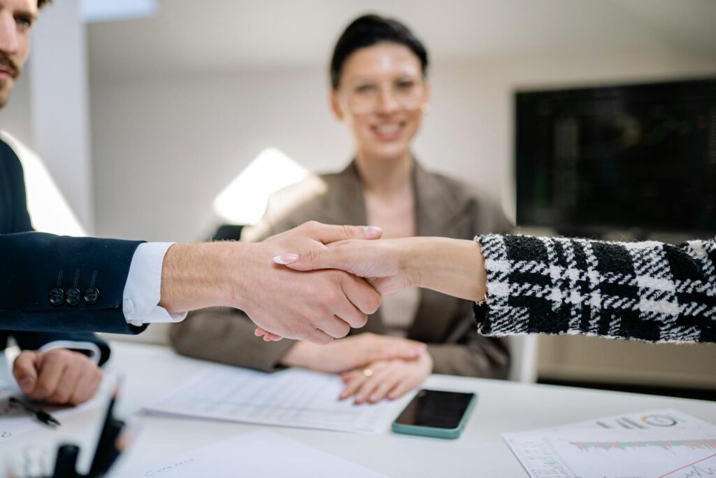 Two business people shaking hands across a desk