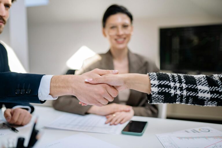 Two business people shaking hands across a desk